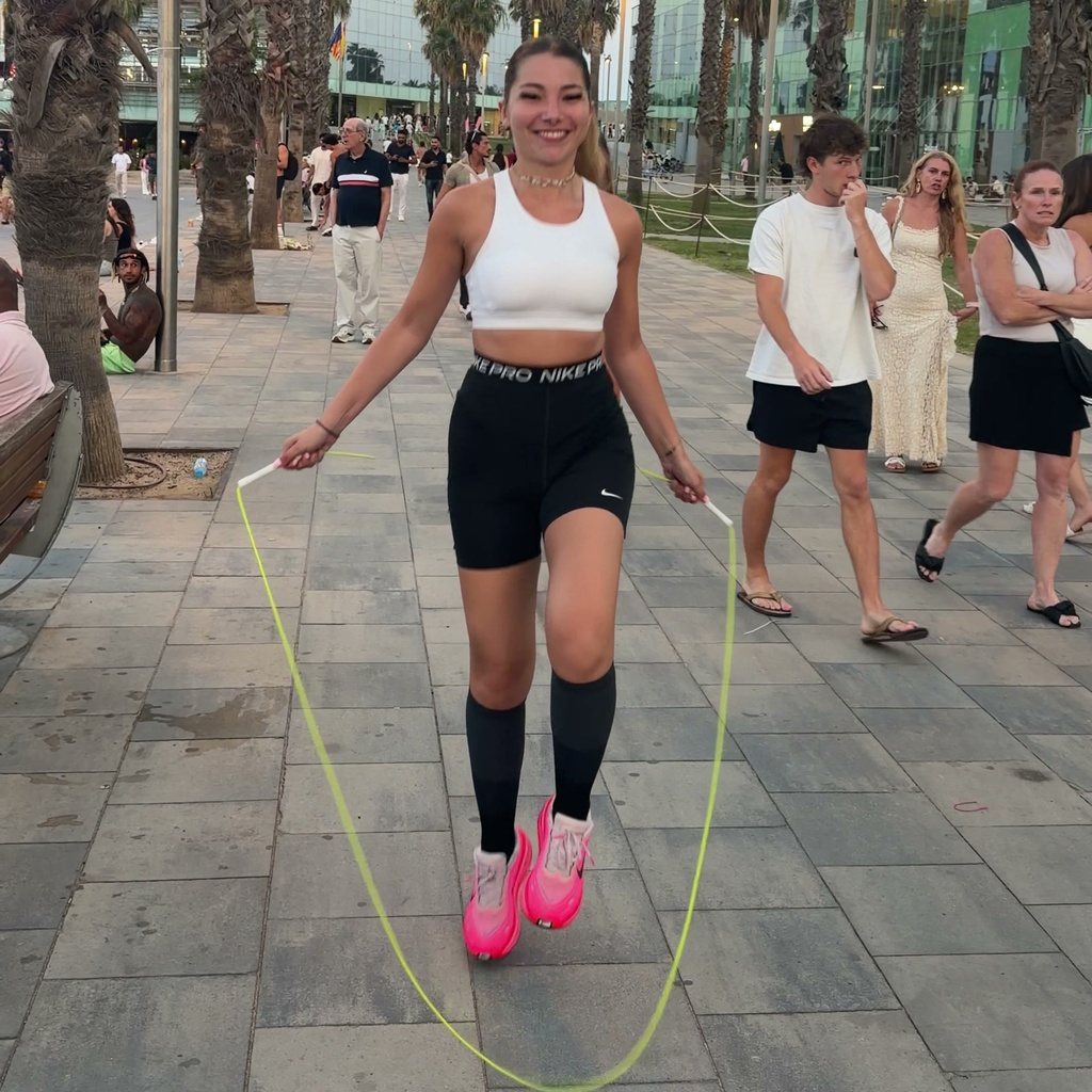 Une élève saute à la corde en souriant, la corde passe sous ses pieds